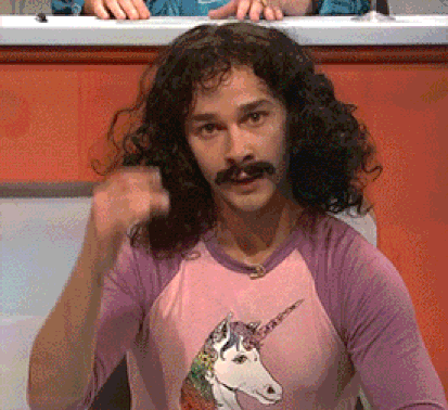 Shia LeBoeuf wearing a mustache and a pink unicorn shirt emphatically saying "Magic" and making a gesture with his hand